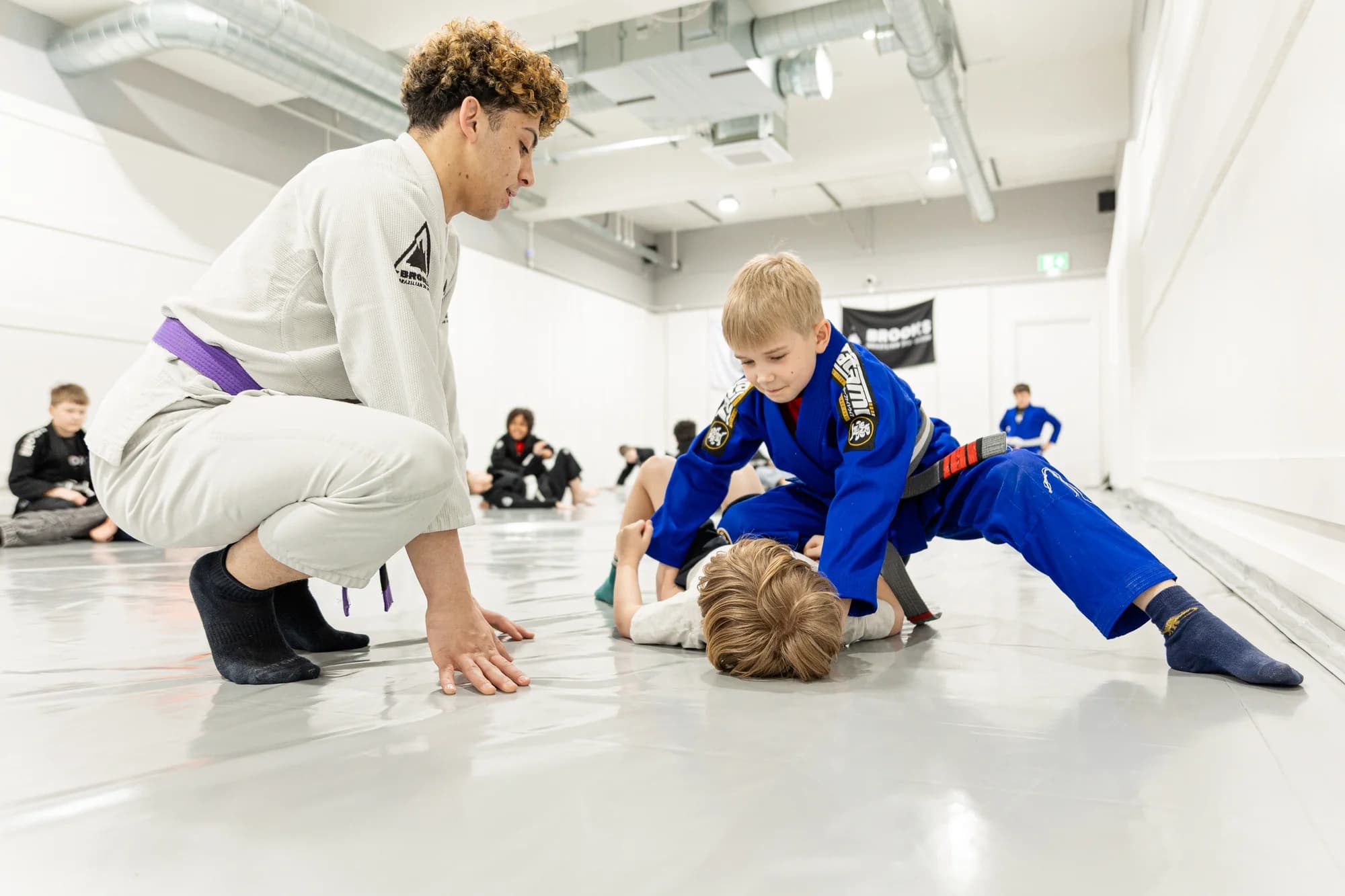 Coach instructing children during a Brazilian Jiu-Jitsu class